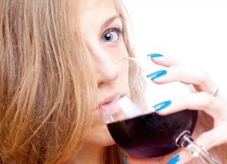 Beautiful young girl drinking wine, on the white background